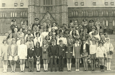 Black and white photo of a large group of Guelph-area School Safety Patrollers and Guelph police officers, posing in front of Parliament Hill, 1969. 