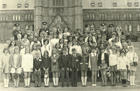 Photo en noir et blanc d’un grand groupe de brigadiers scolaires et de policiers de la région de Guelph posés à la Colline du Parlement en 1969.