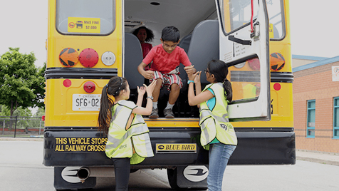 CAA School Safety Patrollers are helping a student get of the bus safely.